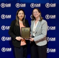 Two women standing on stage showing a plaque to the audience