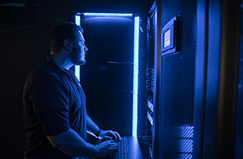 Cybersecurity professional typing on a keyboard while working in a data center.