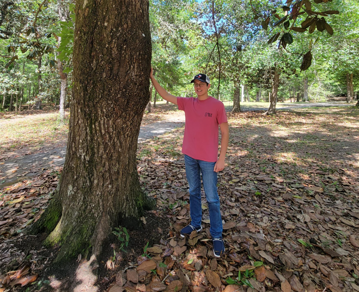 Student standing next to a tree of the UWF campus