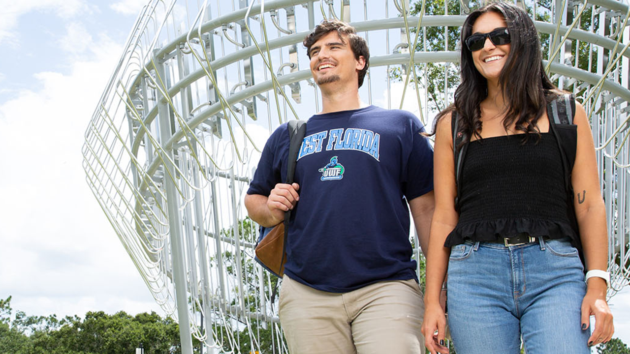 Students walking on campus by an art installation
