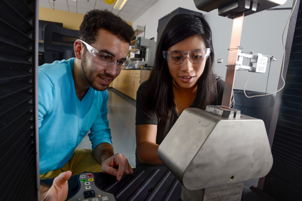 two students working with mechanical engineering machine