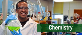 Chemistry student wearing lab safety equipment while holding a beaker with chemical liquid.