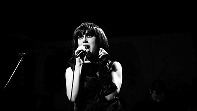 Black and white image of vocalist singing at the mic