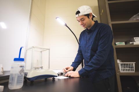 An individual in a white baseball cap and a blue shirt is shown working on isotope analysis