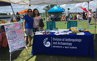 Dr. Marten in a blue shirt and shorts along with a student participate in a coloring activity at the Healthy Start Day of Play in 2019