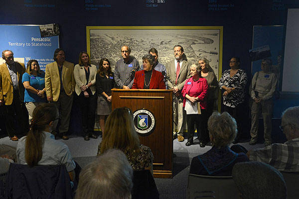 dr judy bense speaking at a podium during the luna press conference