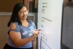 A student writing on a smart board display.