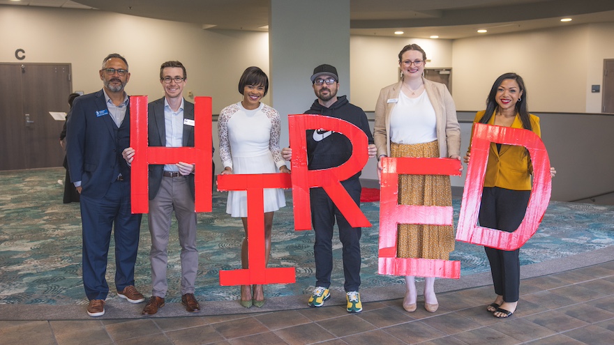Students holding red letters that spell HIRED.