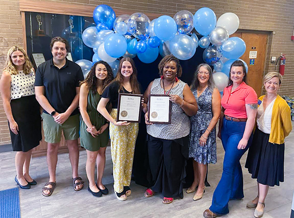 A group of students and faculty members holding awards
