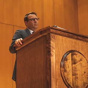 Dr. Joseph Postell standing at a large wooden lectern.