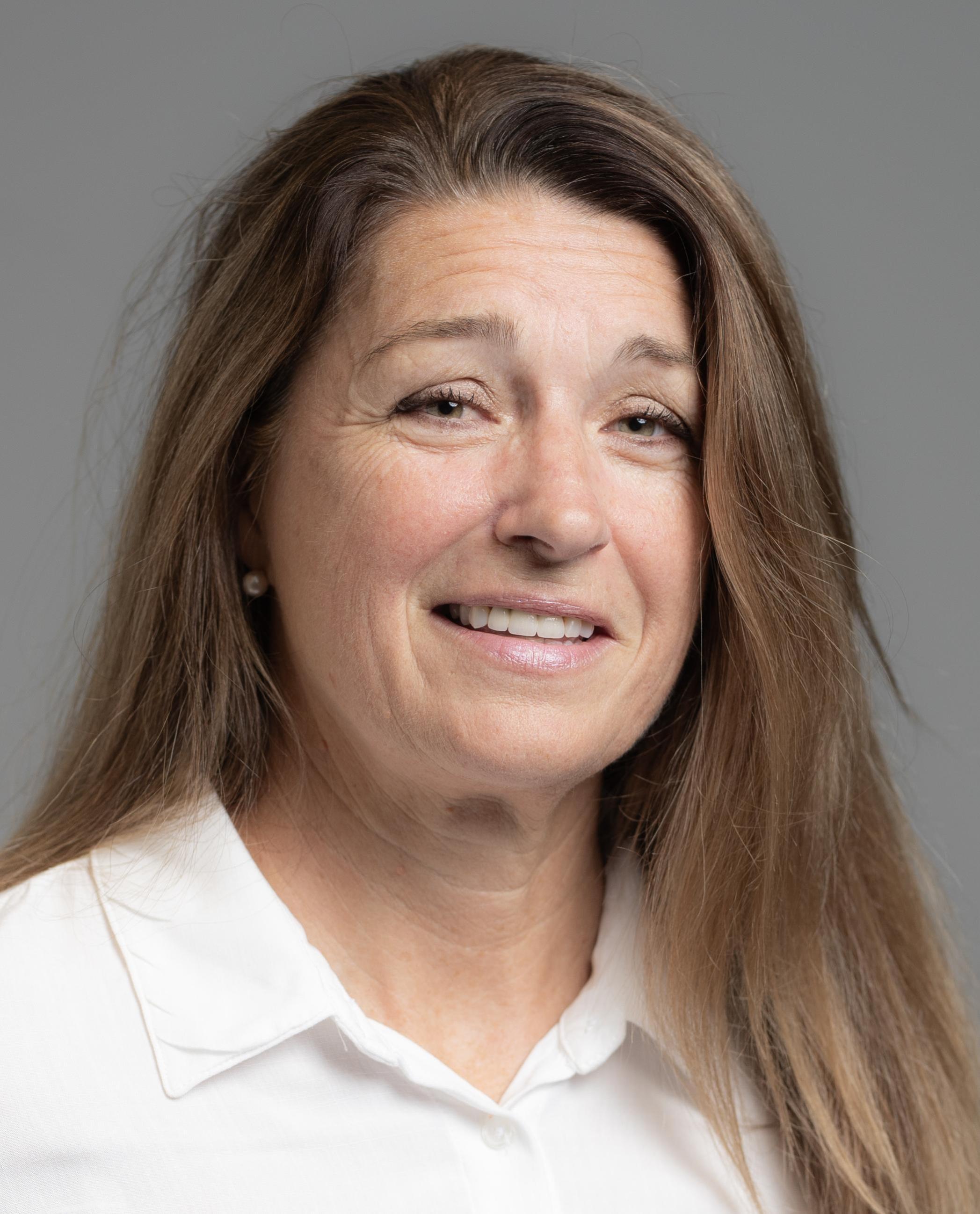 Lee Gaul indoor headshot in a white polo against a gray background.