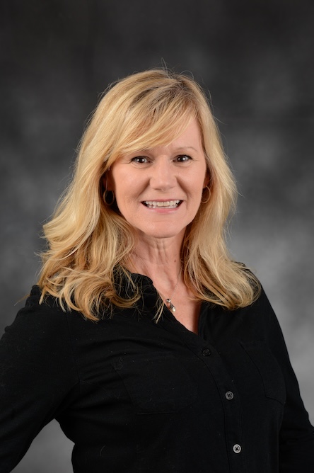 A faculty member with long blond hair in a black top.
