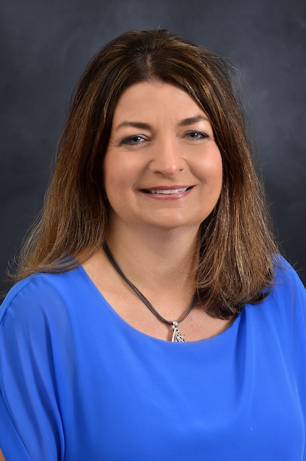 A staff member in a blue top with long brown hair.