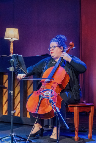 An alumni playing a cello on stage.