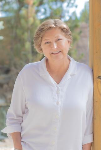 Adjunct Instructor leaning against a post in front of trees.
