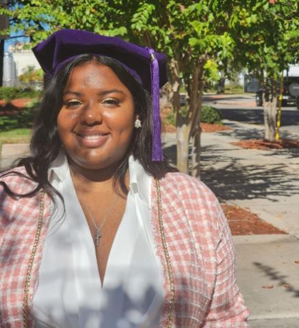 Alumna in a pink jacket in front of a tree