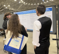 Three students standing in front of a research project poster.