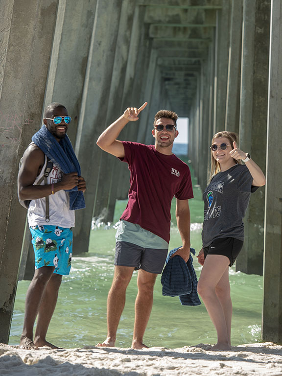 Three UWF students under the pier at Pensacola Beach.