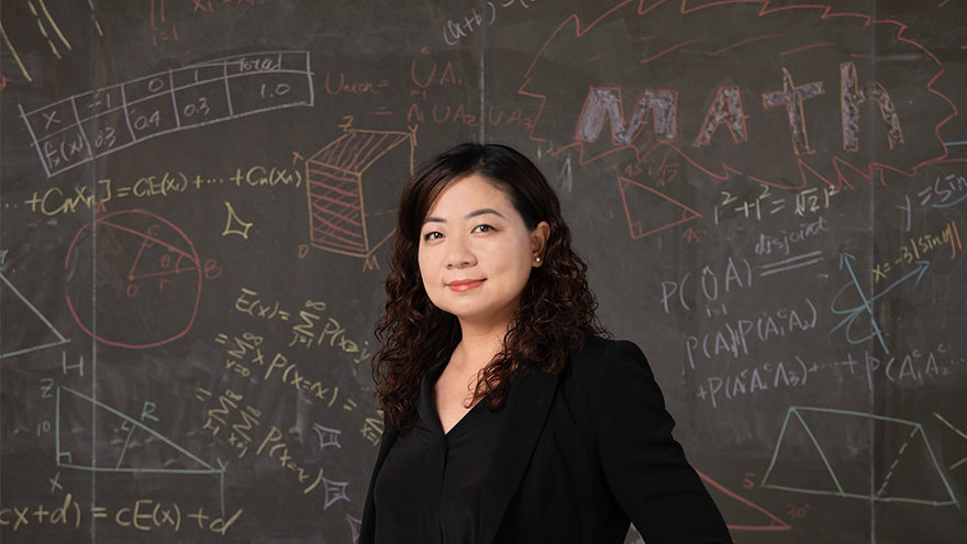 Dr. Liu standing in front of outdoor blackboard