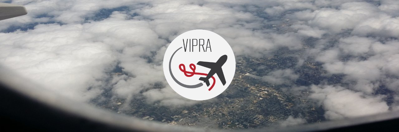 VIRPA logo overlayed on top of a view from an airplane window of clouds over a city.