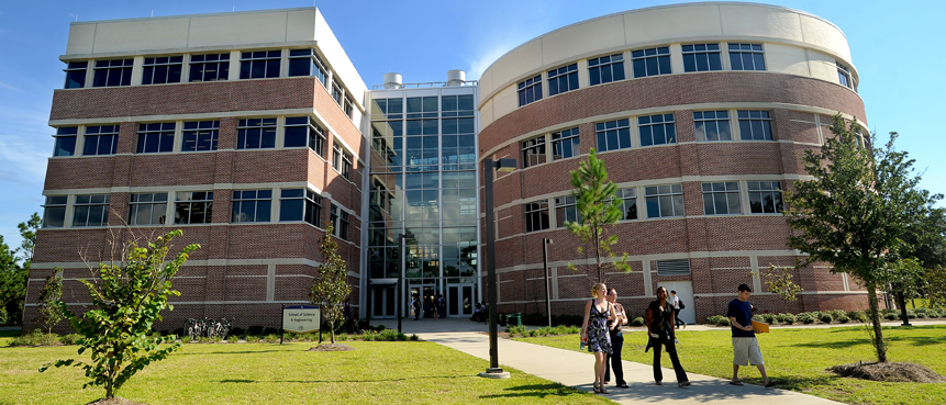 Four students walking as a group away from Building 4, a four story building on the UWF Pensacola campus.