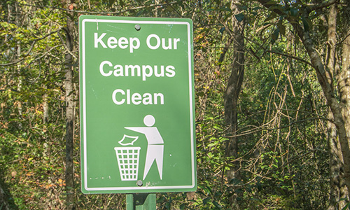 Keep Our Campus Clean metal sign in front of trees.