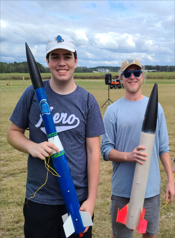 two students holding rockets they built