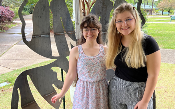 Two students standing in front of metal cut out of oversized butterfly