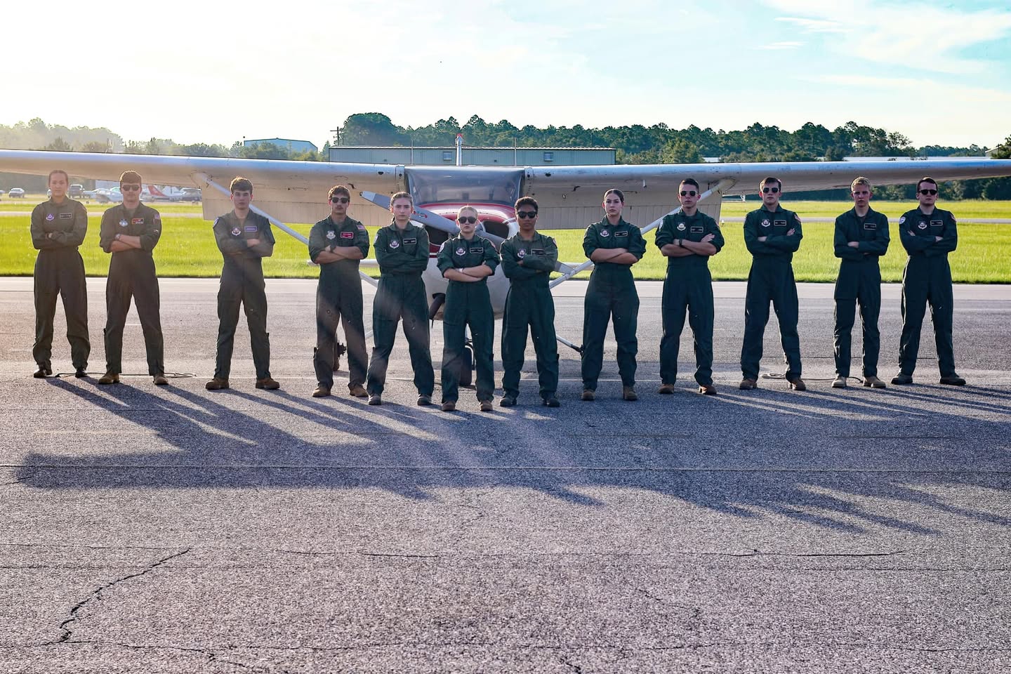 Group shot of high school students posed in front of an airplane