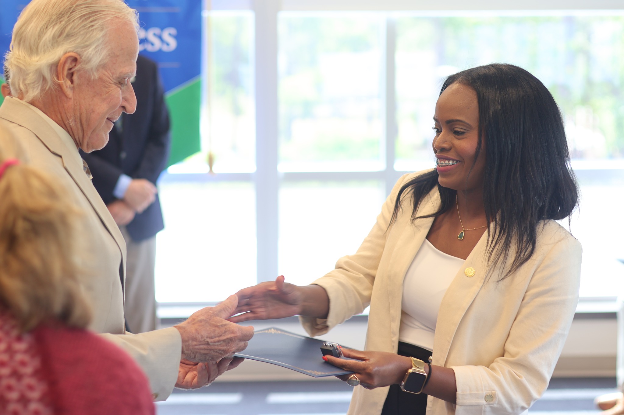 Student shaking professor's hand while accepting a Beta Gamma Sigma certificate