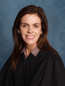 Headshot of woman with long brown hair dressed in black judge's robe