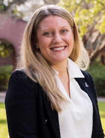 A woman standing in front of a tree and brick archway