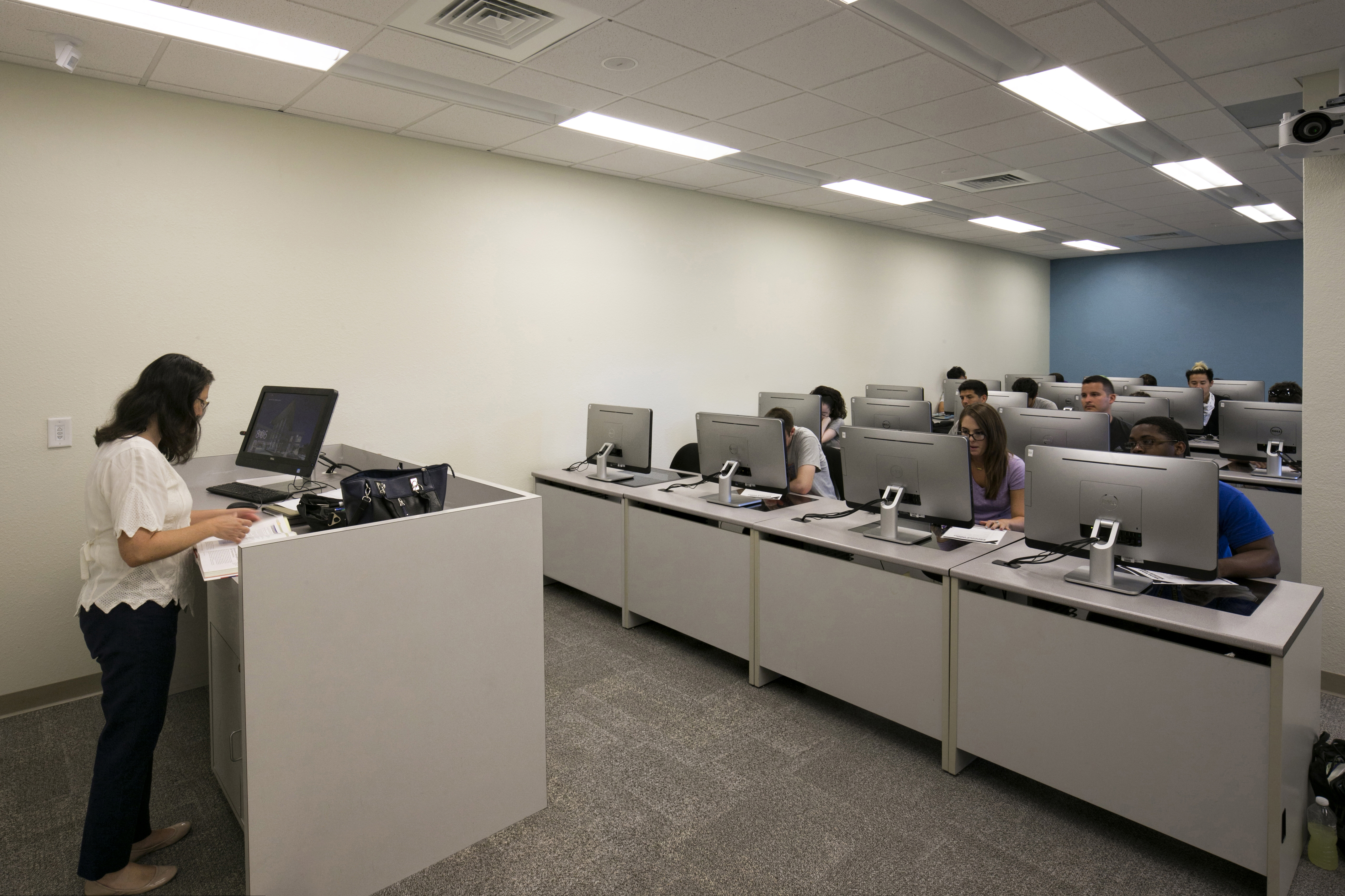 Professor lecturing in front of a class of students in the Building 76 computer classroom.