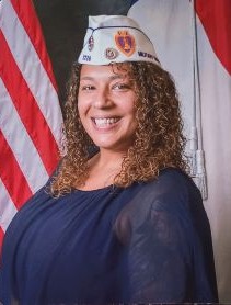 Headshot wearing white hat posed in front of American flag