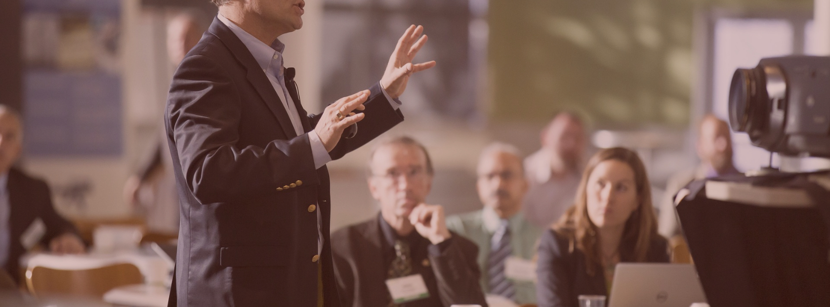 Person in professional attire speaking to a small crowd.