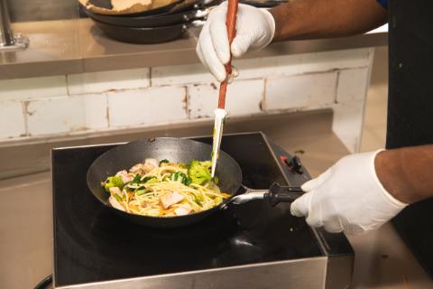 Argo Food Co worker cooking chicken stir fry in a pan