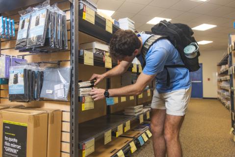 Student looking through textbooks on a shelf