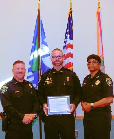 Three UWF police staff, middle officer receiving a distinguished service award