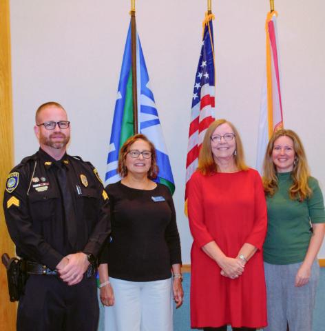 four UWF staff/faculty standing in front of flags