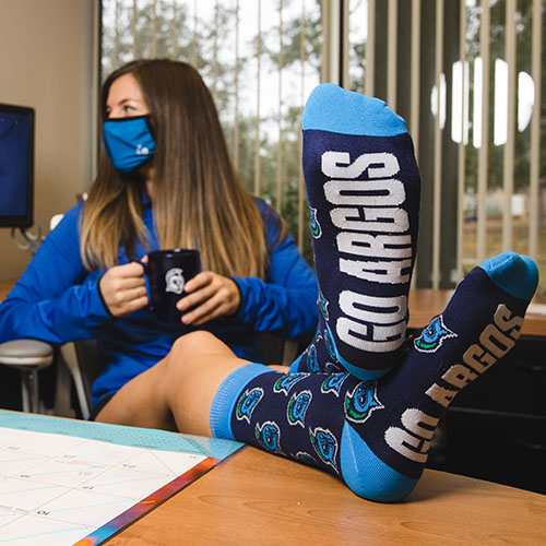uwf staff member showing off donor drive socks that say go argos
