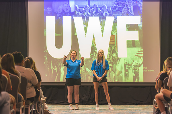 Two UWF orientation leaders presenting a slidedown during an orientation event to a group of students.