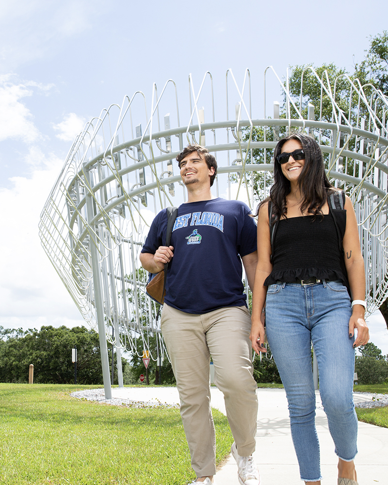 Students walking on campus by an art installation