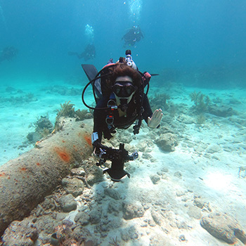 Nicole Grinnan scuba diving under water with a camera.