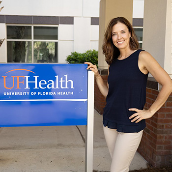 Ali Andrus next to a University of Florida Health sign in a building outdoor plaza.