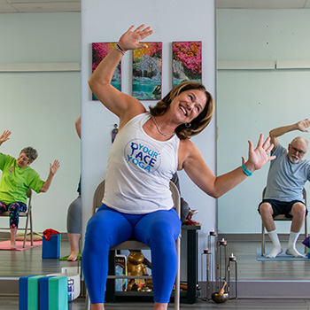 Jebbye Bonnet Lemons leading a yoga class in a yoga studio.