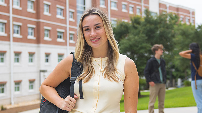 Smiling UWF student stands near student housing