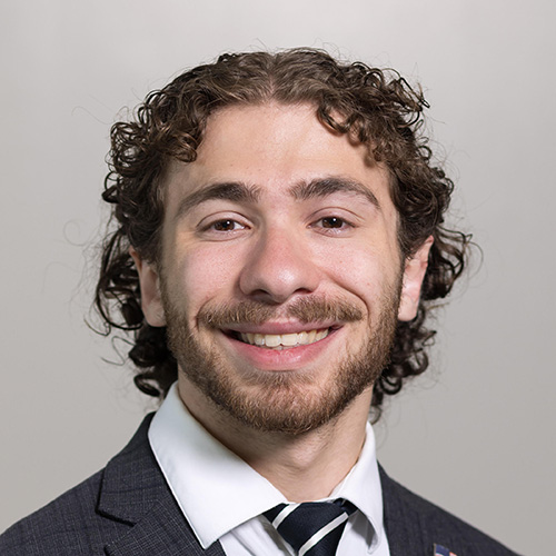 Eli Schatz indoor headshot in suit and tie attire.