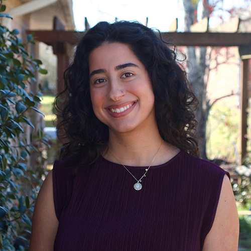 Ghada Eqab smiling at the camera while standing outdoors.