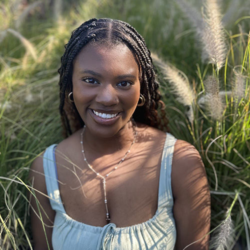 Jadyn Scaife smiling at the camera while sitting in high grass.