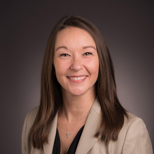 Dr. Renée Davis indoor headshot in a tan jacket over a black top against a brown background.
